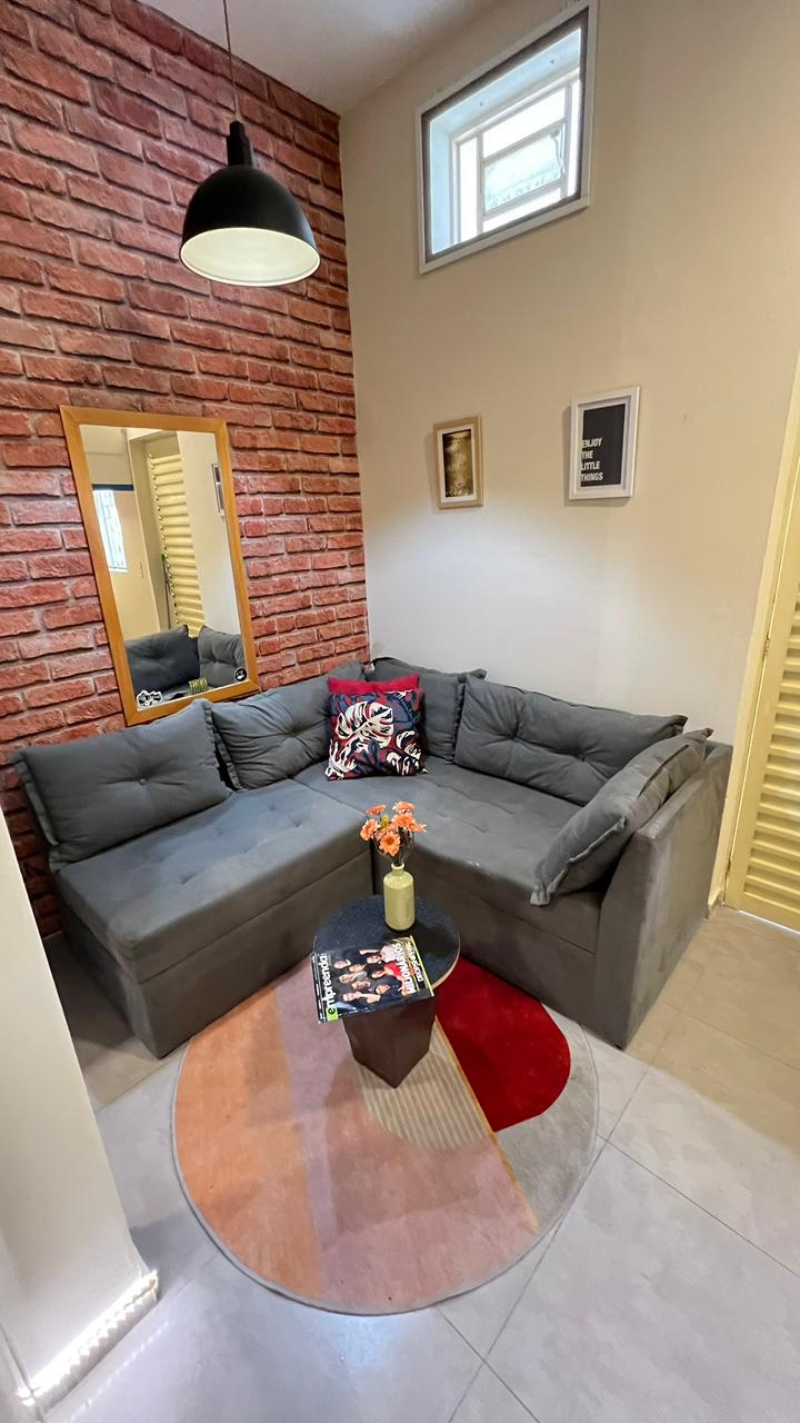 Sala real de uma kitnet com parede de tijolos